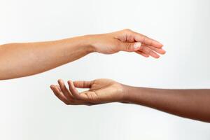 Hands with different skin colour, one african-american, one caucasian, touching each other on gary background. photo