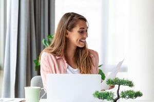 enfocado negocio mujer utilizando ordenador portátil a hogar, mirando a pantalla, charlando, leyendo o escritura correo electrónico, sentado en sofá, hembra estudiante haciendo tarea, trabajando en investigación proyecto en línea foto