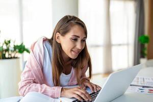 joven mujer trabajando ordenador portátil. negocio mujer ocupado trabajando en ordenador portátil computadora a oficina. mujer de negocios sentado a brillante moderno trabajo estación y mecanografía en ordenador portátil foto