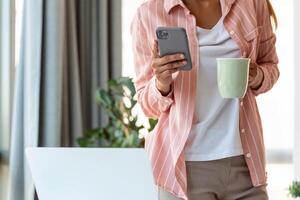 Young business women standing at office and drink coffee looking at smartphone. photo