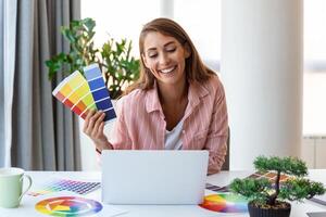 alegre youn mujer diseñador teniendo vídeo conferencia con clientela, sentado a escritorio en frente de computadora, participación color paletas, gesticulando y sonriente, Copiar espacio foto