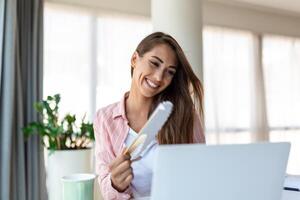 Tired overheated young woman hold wave fan suffer from heat sweating indoor work on laptop at home office, annoyed woman feel uncomfortable hot summer weather problem no air conditioner concept photo