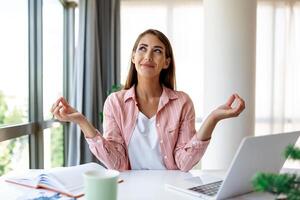 calma mujer relajante meditando con computadora portátil, No estrés gratis alivio a trabajo concepto, consciente de pacífico joven mujer de negocios o estudiante practicando respiración yoga ejercicios a lugar de trabajo, oficina meditación foto