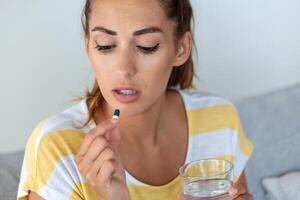 Woman takes medicines with glass of water. Daily norm of vitamins, effective drugs, modern pharmacy for body and mental health concept photo