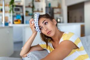 Close-up shot of a woman suffering from a headache cooling her head with a ice pack photo