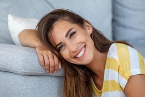 Happy young woman sitting on sofa at home Portrait of beautiful woman smiling and relaxing during summer. photo