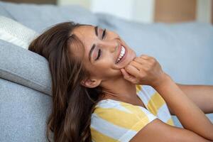 Happy young woman sitting on sofa at home Portrait of beautiful woman smiling and relaxing during summer. photo