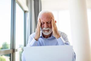 Businessman office working holding sore head pain from desk working and sitting all day using laptop computer or notebook suffering headache sick worker overworking concept photo