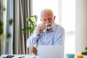 Senior businessman crying working and sitting all day using laptop computer or notebook suffering headache sick worker overworking concept photo