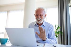 Portrait of handsome senior business coach having video call, talking to camera, explaining something. Webinar, video conferencing, online meeting concept photo