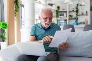 Surprised laughing happy old mature retired man looking through paper document, feeling excited analyzing financial information, getting taxes refund or bank loan approval at home. photo