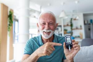 Blood sugar testing at home. Checking Blood Sugar Level At Home. Diabetic Checking Blood Sugar Levels. Senior man checking blood sugar level by glucometer and test stripe at home photo