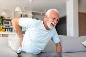 mayor mayor hombre conmovedor su atrás, sufrimiento desde dolor de espalda, ciática, sedentario estilo de vida concepto. espina salud problemas. cuidado de la salud, seguro foto