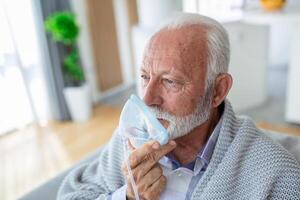 enfermo mayor hombre haciendo inhalación, medicina es el mejor medicamento. enfermo mayor hombre vistiendo un oxígeno máscara y pasando tratamiento para COVID-19. mayor hombre con un inhalador foto