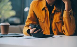 Asian businesswoman in formal suit in office happy and cheerful during using smartphone and working photo