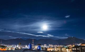 dramático Disparo de paisaje urbano a bogota con un lleno Luna terminado el noche cielo terminado el colinas foto