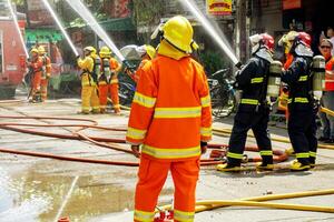 Lampang, Thailand, 2018 -  Firefighters group of Lampang city confederate water spray and control the hoses to quench the fire in the real annual rehearsal fire drill in urban city. photo