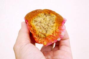 Closeup hand holding Thai ancient eggs cupcake was eaten isolate on pink background. photo