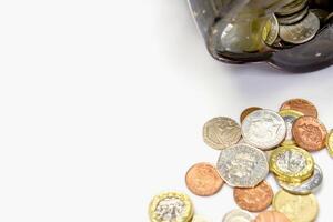 Top view and crop of British currency coins open from the piggy bank laid out scattered on right with copy space for texts and white background. photo