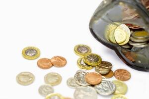 British currency coins open from the piggy bank laid out scattered on white background. photo