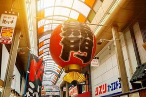 Osaka City, Japan, 2018 - Decorate big red Japanese paper lantern hanging on the entrance at Kuromon Ichiba fresh market, Osaka, Japan with sun flare background. photo