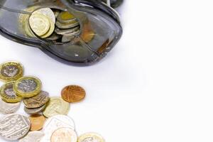 Top view and crop of British currency coins open from the piggy bank laid out scattered on left with copy space for texts and white background. photo