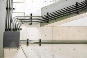 Design and Structure of pipe electric wires and control box with natural sun lights on building wall background. photo