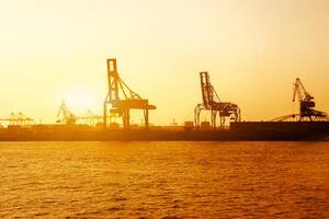 Silhouette of container and gantry crane at Osaka port are loading on evening with sunset glow background. photo