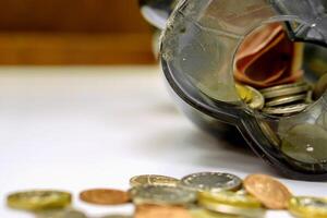 de cerca de británico moneda monedas abierto desde el cerdito banco puesto fuera dispersado en blanco mesa y de madera antecedentes. foto