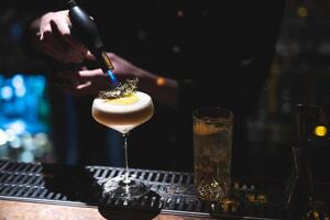 the bartender prepares a beautiful alcoholic cocktail at the bar counter photo