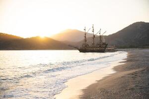 a large ship is docked at the seashore at sunset and beautiful mountains photo