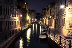 view into a small canal in Venice at night photo