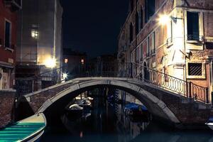 Venice canal late at night with street light illuminating bridge and houses photo