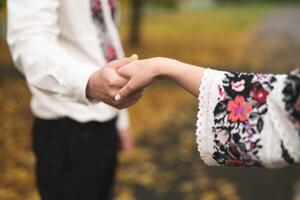 the bride and groom are holding hands with a bouquet of flowers and in traditional Ukrainian clothes photo