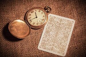a still life of four playing cards on burlap and a beautiful still life with old books and a clock photo