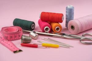 various tailor accessories and tools for tailoring on a pink background photo