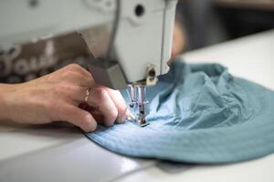 trabajadores en un industrial prenda fábrica coser ropa en de coser máquina foto