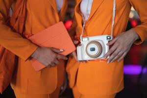 two female promoters in identical suits with a camera and a tablet photo