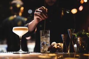 the bartender prepares a beautiful alcoholic cocktail at the bar counter photo