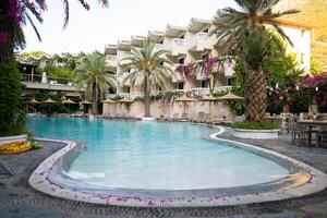 a large outdoor pool on the hotel grounds with blue water and palm trees photo