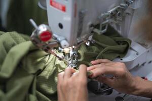 trabajadores en un industrial prenda fábrica coser ropa en de coser máquina foto