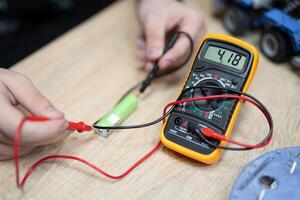 the engineer measures the voltage on the battery with a multimeter photo