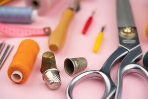 various tailor accessories and tools for tailoring on a pink background photo