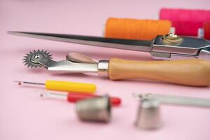 various tailor accessories and tools for tailoring on a pink background photo