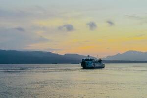 Ferry crossing the Bali Strait at sunrise. Passenger transport ship. Summer and spring holiday concept. Public water transportation. photo