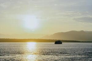 Ferry crossing the Bali Strait at sunrise. Passenger transport ship. Summer and spring holiday concept. Public water transportation. photo