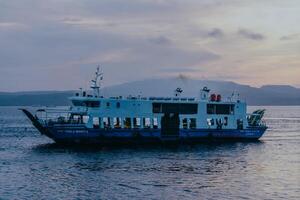 Ferry crossing the Bali Strait at sunrise. Passenger transport ship. Summer and spring holiday concept. Public water transportation. photo