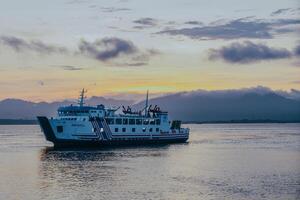 Ferry crossing the Bali Strait at sunrise. Passenger transport ship. Summer and spring holiday concept. Public water transportation. photo