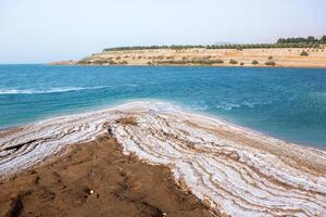 View of Dead Sea coastline at sunset time in Jordan. Salt crystals at sunset. Dead sea landscape with mineral structures. photo