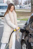joven mujer repostaje coche con gasolina a gas estación. eco combustible concepto. el concepto de ambientalmente simpático transporte. foto